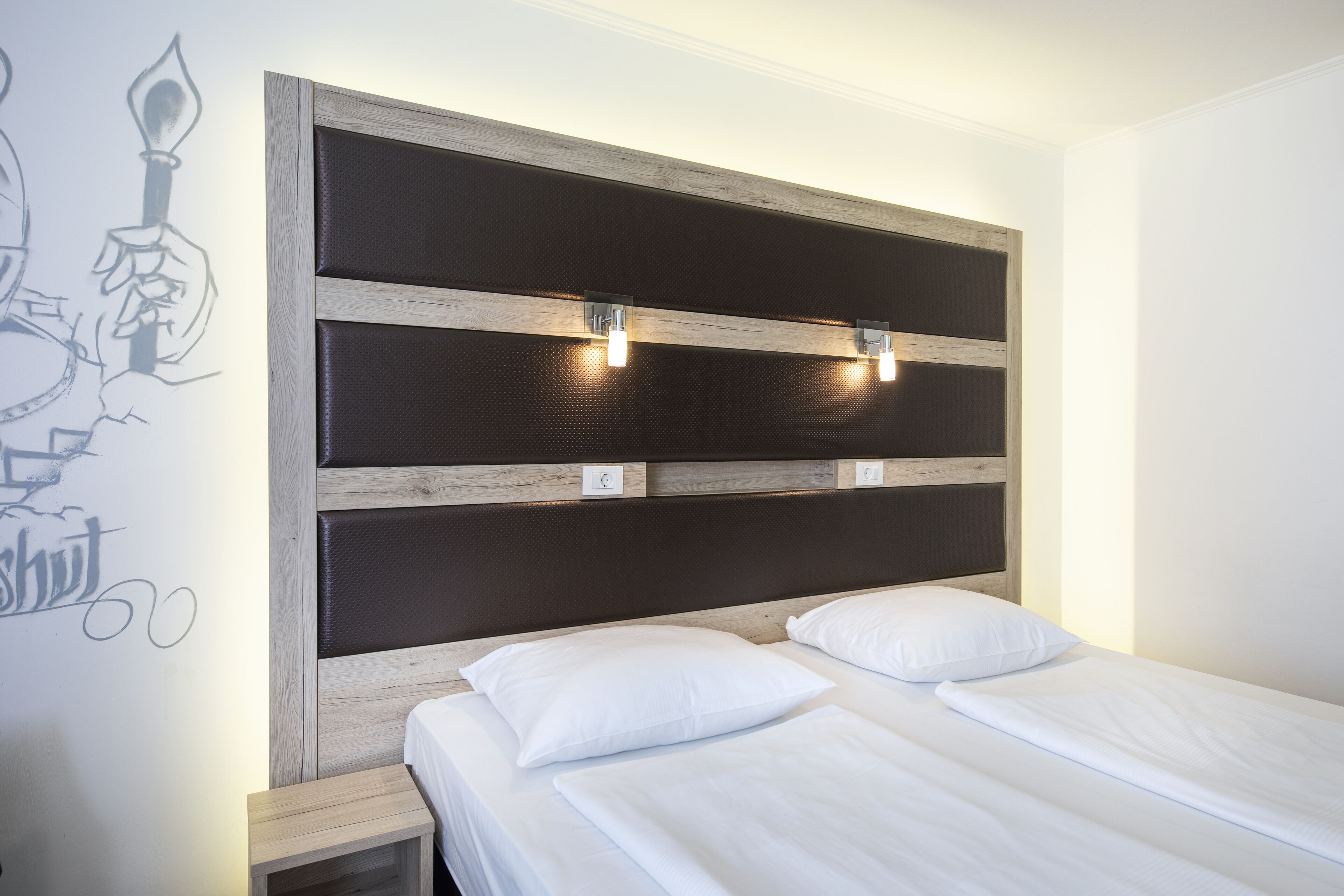 A bedroom with a wooden headboard, two bedside tables, and a bed with white bedding.