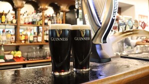 Two Guinness glasses on a bar counter with a tap and a Guinness branded ice bucket in the background. - Novotel Perth Langley (Perth)