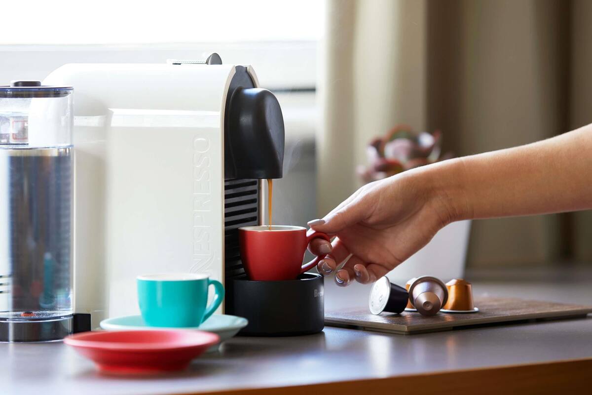 Une machine à café verse du café dans une tasse rouge.