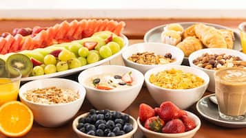 Un bufé de desayuno con diversas frutas, cereales y productos de pastelería.