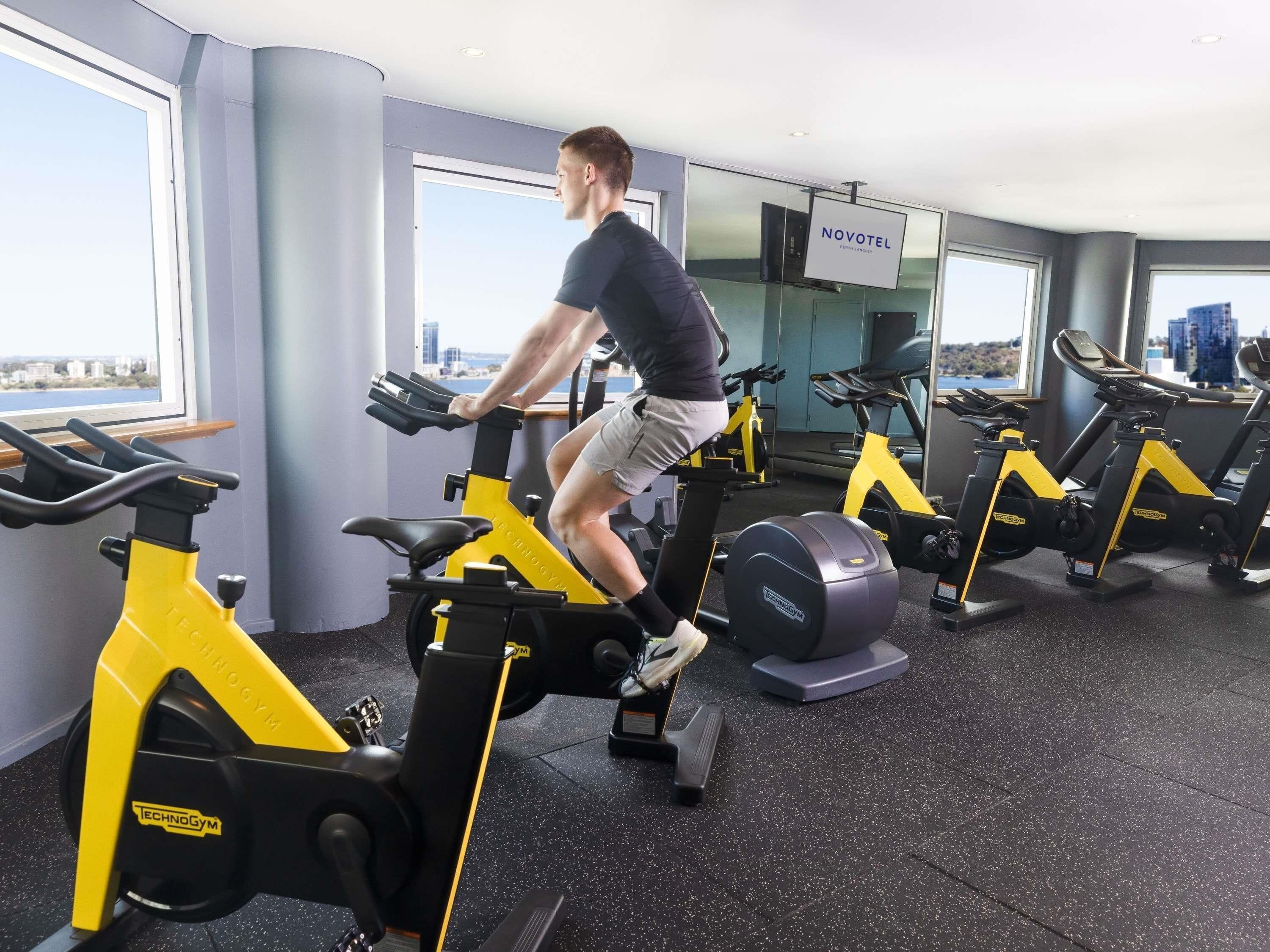 A gym with stationary bikes, a mirror, and a Novotel sign.