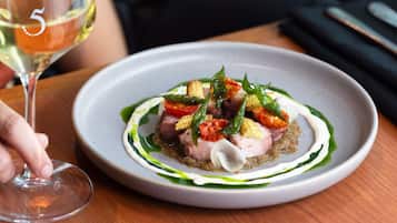 A plate of food with a glass of white wine on a wooden table.