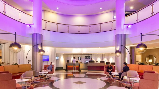 A hotel lobby with a reception desk, seating areas, and a central decorative feature. - Novotel Perth Langley (Perth)