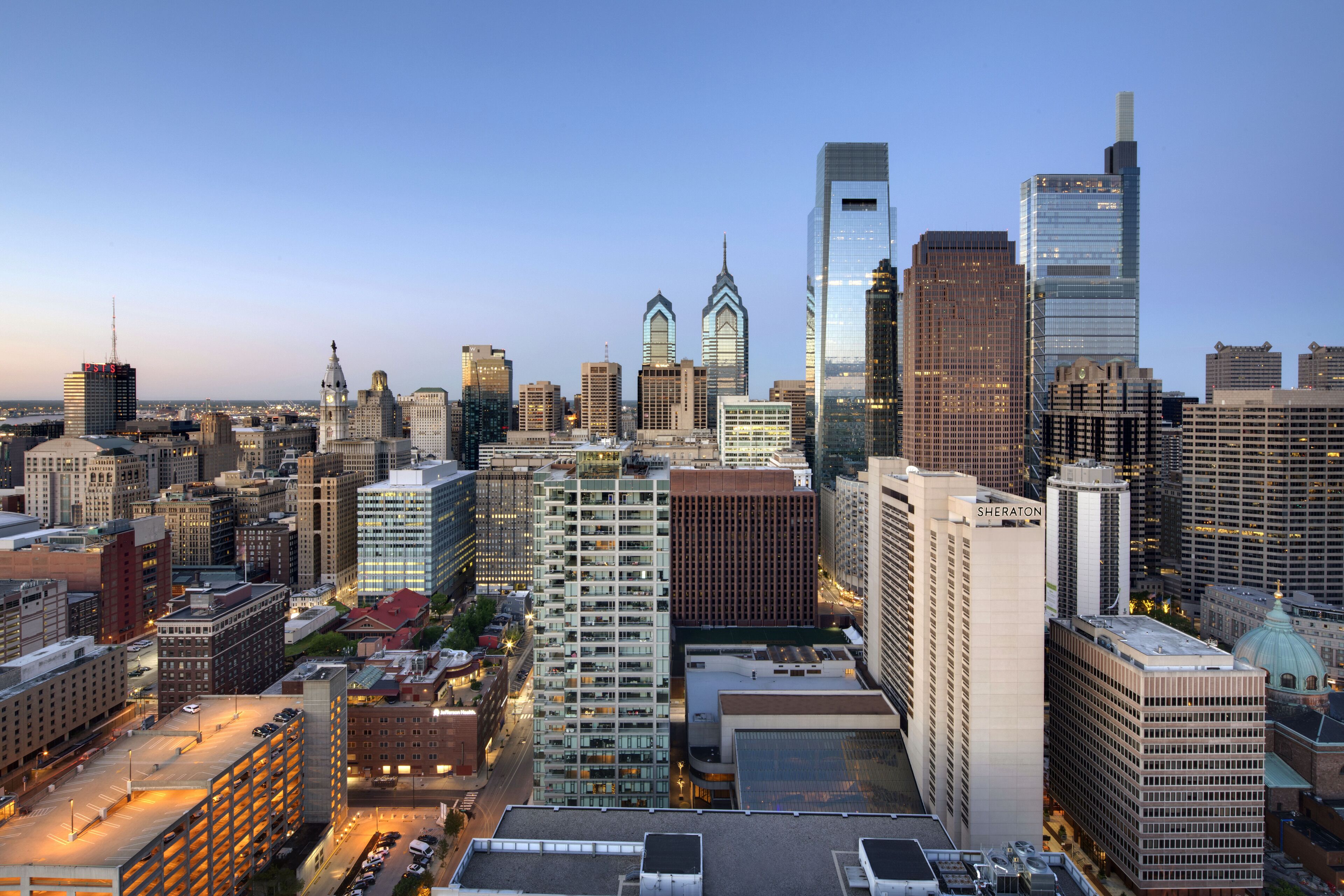 A cityscape with a variety of high-rise buildings, including a prominent skyscraper with a unique architectural design.