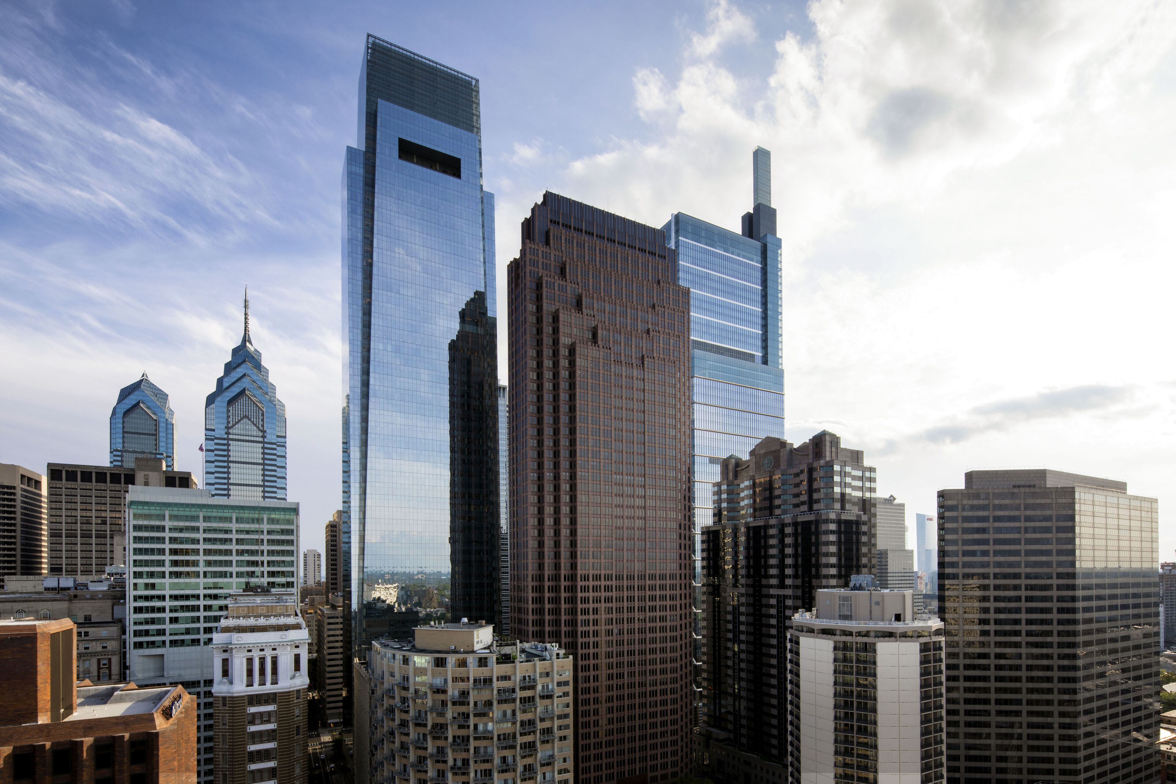 Un paysage urbain comprenant divers immeubles de grande hauteur, notamment un gratte-ciel remarquable à la façade originale et un bâtiment au design distinctif et anguleux.