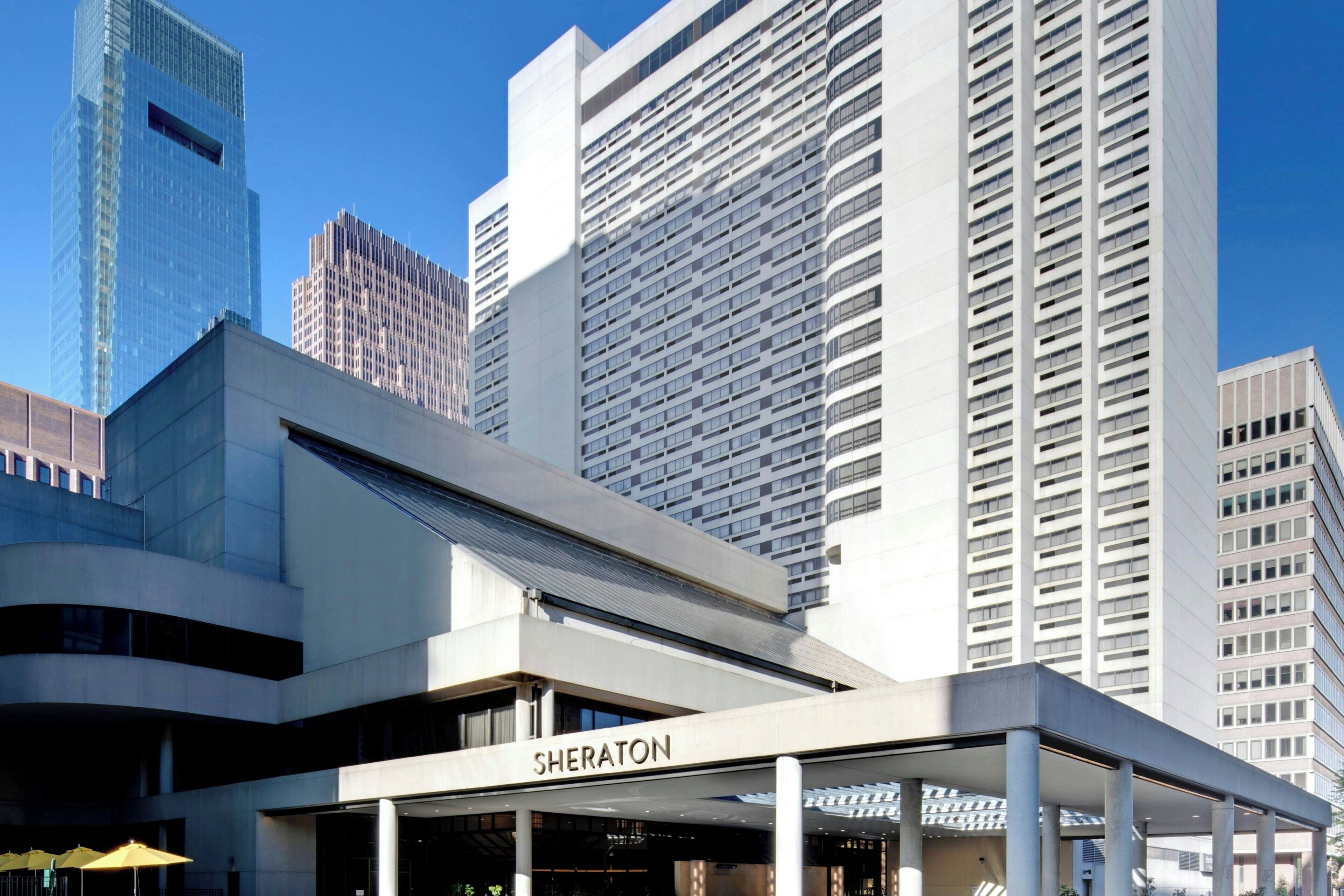 Un hotel Sheraton con un diseño arquitectónico moderno, que presenta una entrada destacada y un frente de vidrio.