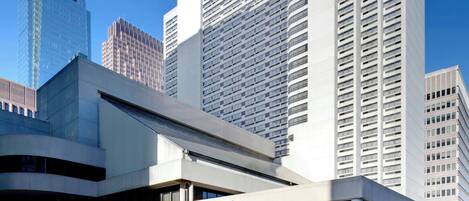 Un hotel Sheraton con un diseño arquitectónico moderno, que presenta una entrada destacada y un frente de vidrio.