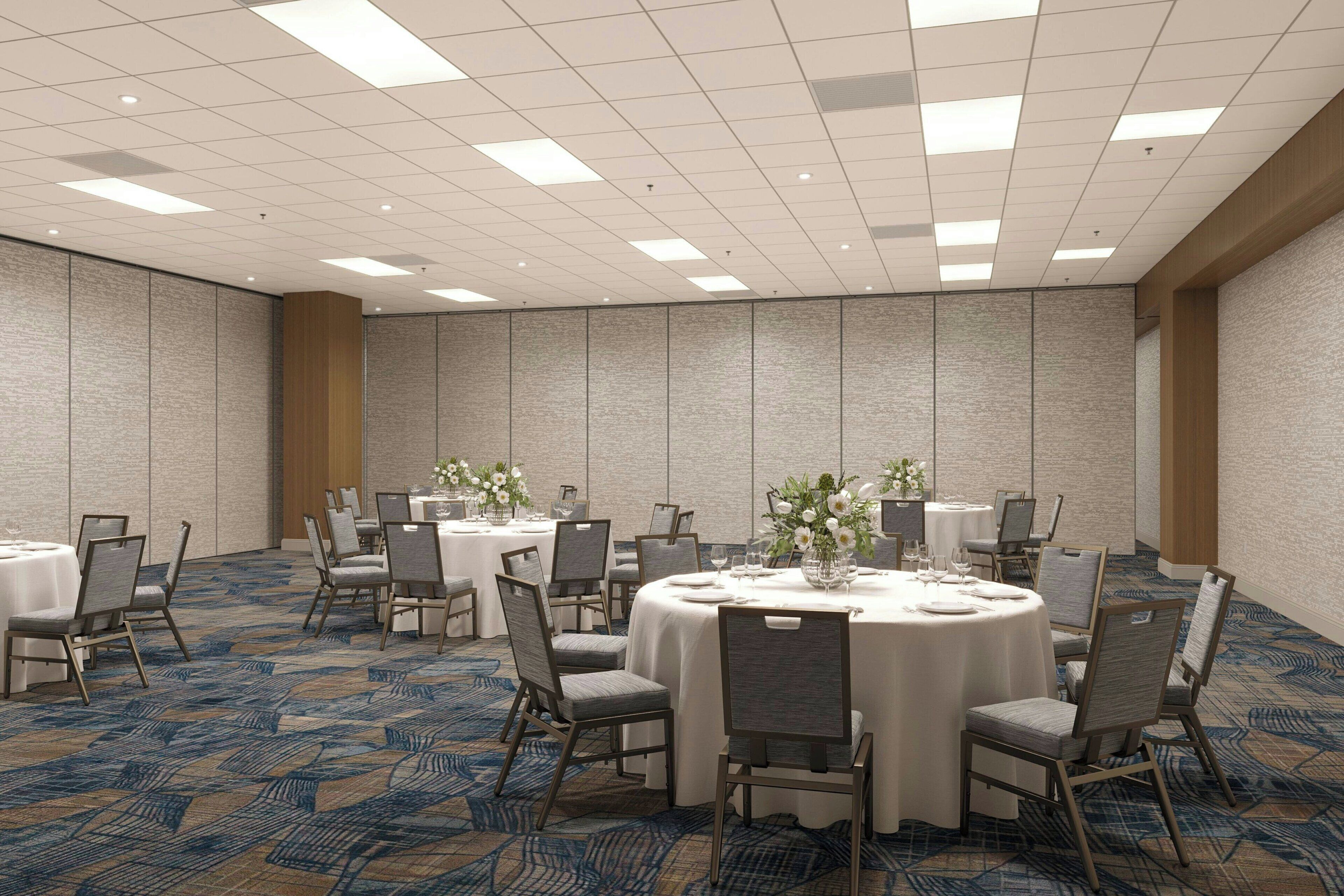 A conference room with round tables, chairs, and floral centerpieces.