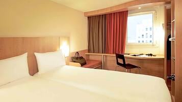 Une chambre d’hôtel avec un grand lit, un bureau avec une chaise, une fenêtre avec des rideaux et une armoire.