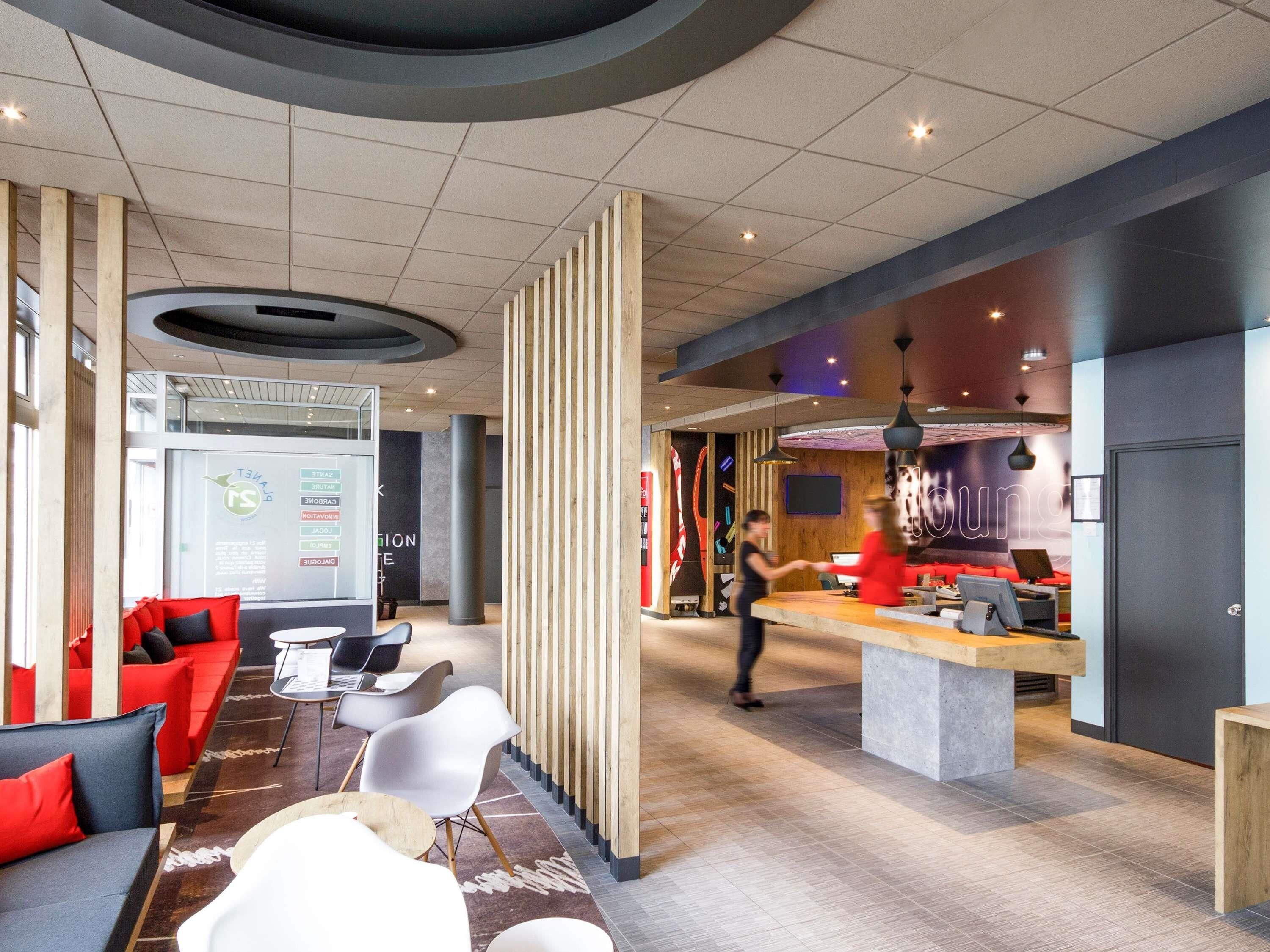 A modern lobby with a reception desk, seating area, and a large screen displaying information.