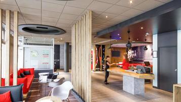 A modern lobby with a reception desk, seating area, and a large screen displaying information.