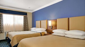 A hotel room with two beds, a window with curtains, a nightstand with a lamp, and a blue accent wall. - Days Inn by Wyndham San Francisco - Lombard (San Francisco)