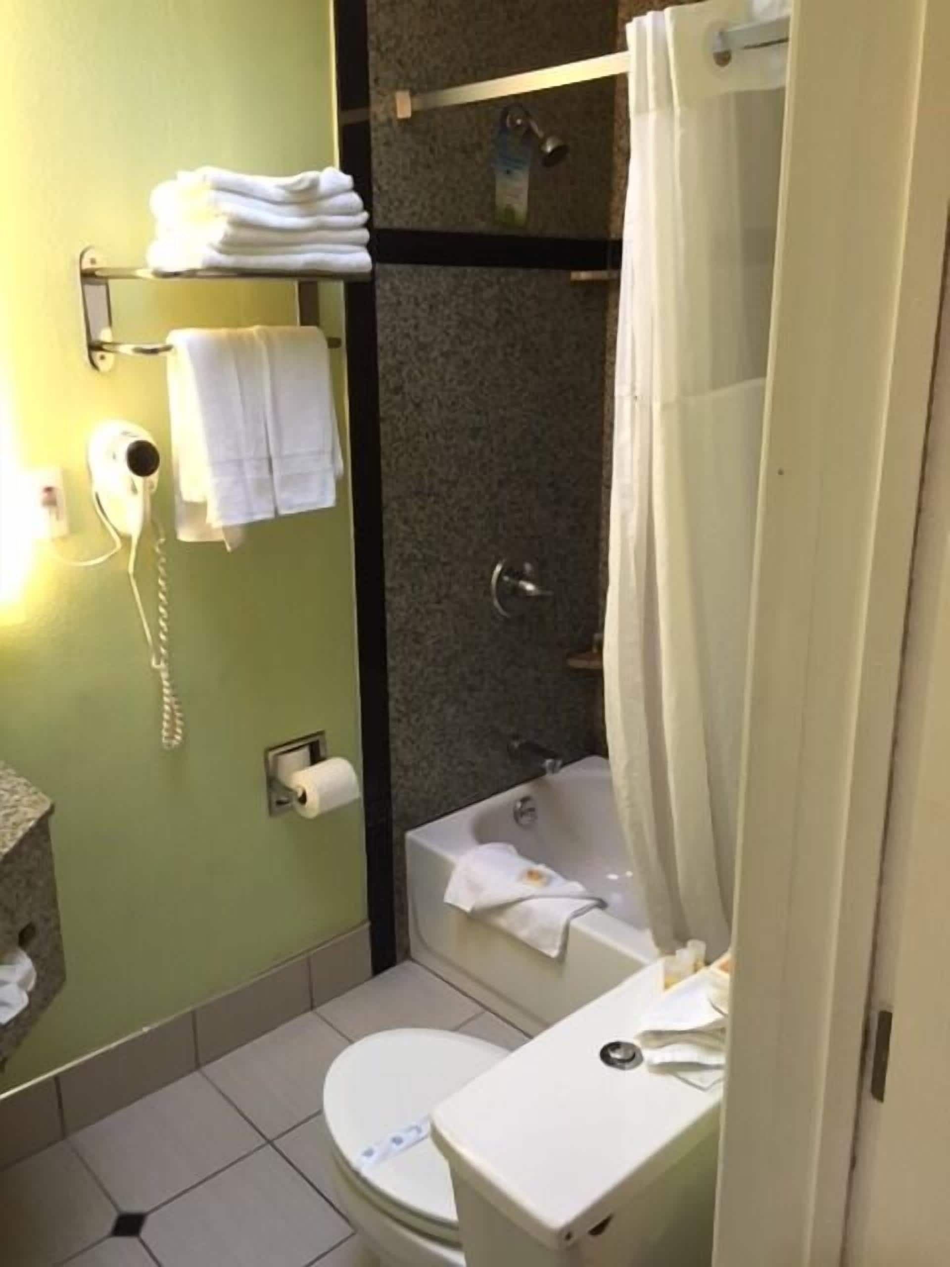 A bathroom with a toilet, a bathtub, a shower area, and a towel rack with folded towels.