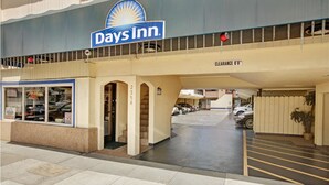 A Days Inn entrance with a clearway sign, a parking area, and a storefront with a signboard. - Days Inn by Wyndham San Francisco - Lombard (San Francisco)