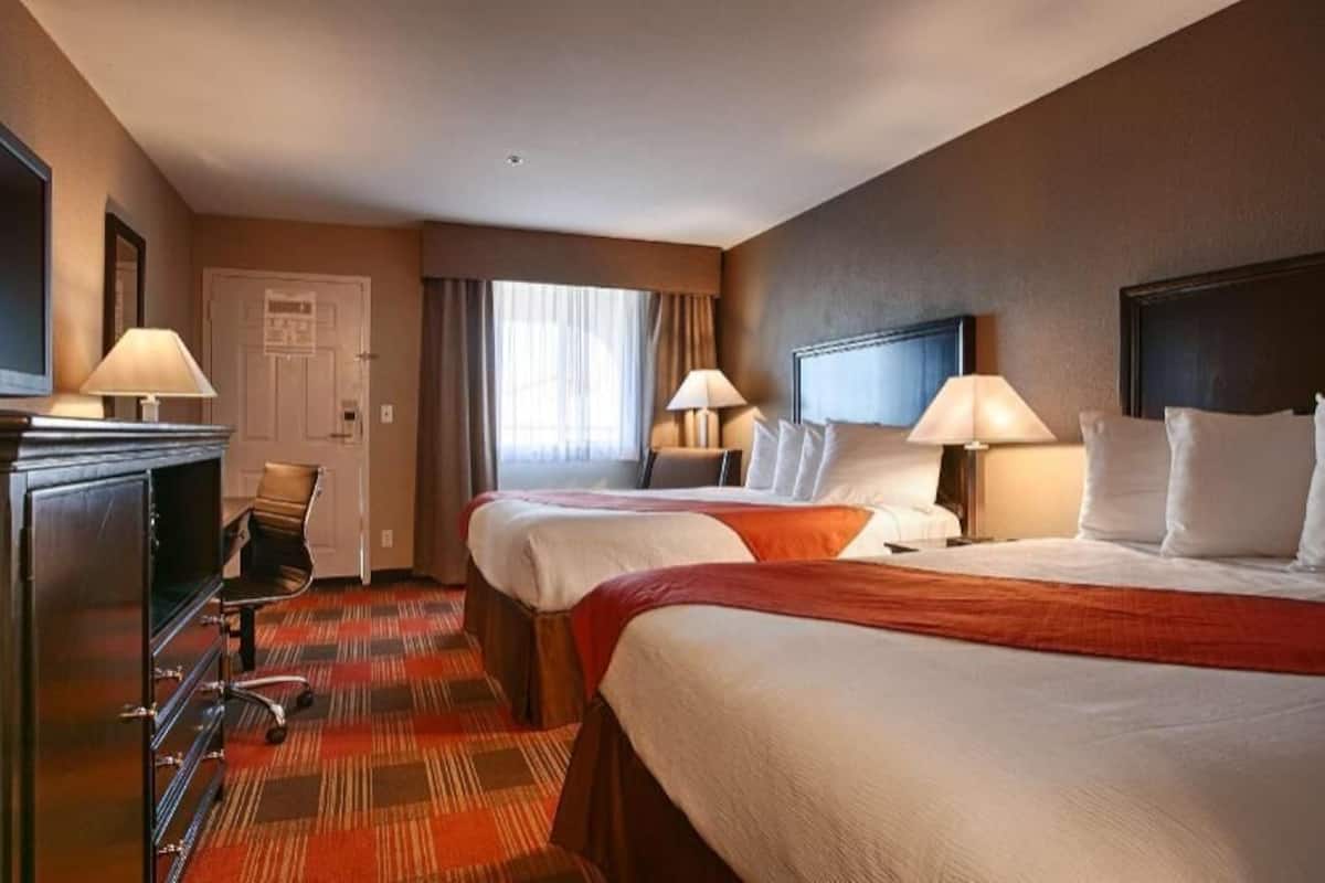 Hotellihuone, jossa on kaksi sänkyä, televisio, työpöytä ja tuoli.