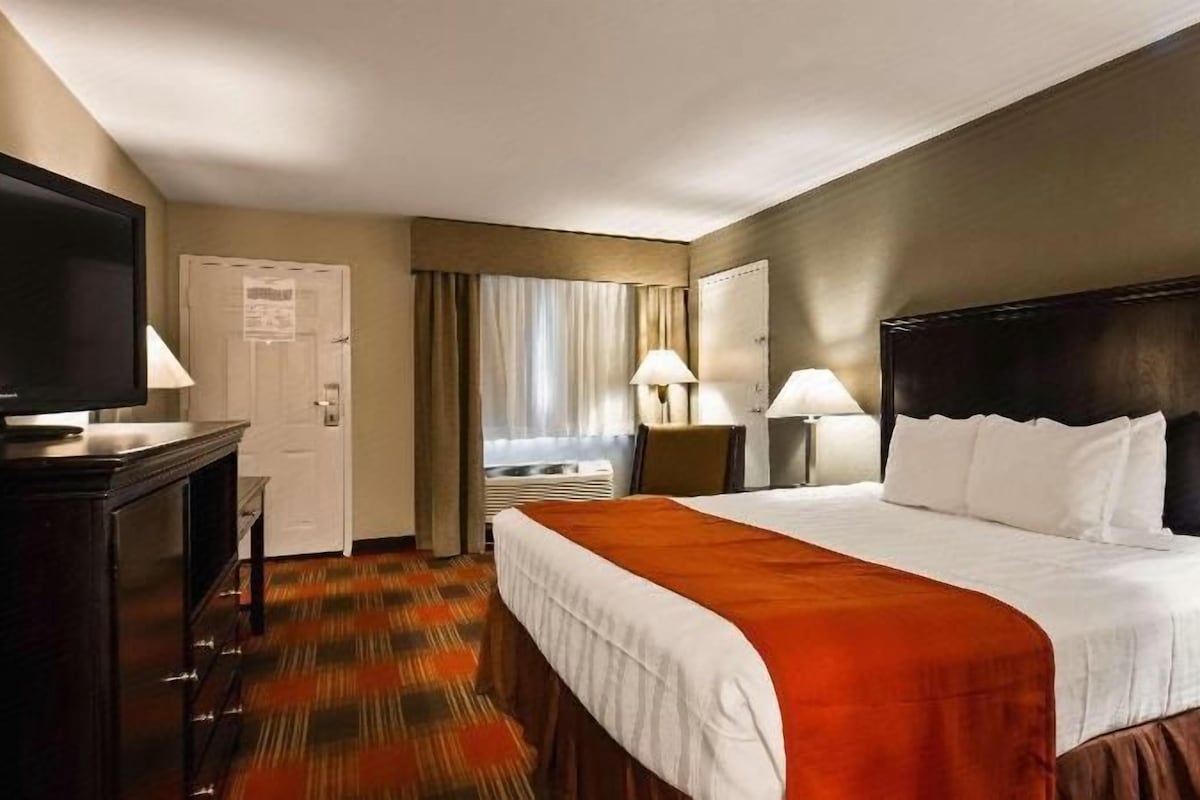 Una habitación de hotel con una cama, televisión, escritorio y una silla.
