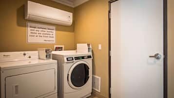 Un área de lavandería con lavadora y secadora Whirlpool, un cartel con información sobre productos de limpieza y un equipo de aire acondicionado.
