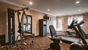 Academia com equipamentos de cardio, máquinas de peso e espelho.