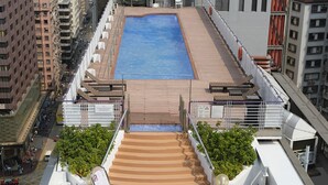 A rooftop pool area with a blue pool, wooden deck, and outdoor seating. - Prudential Hotel (Kowloon)
