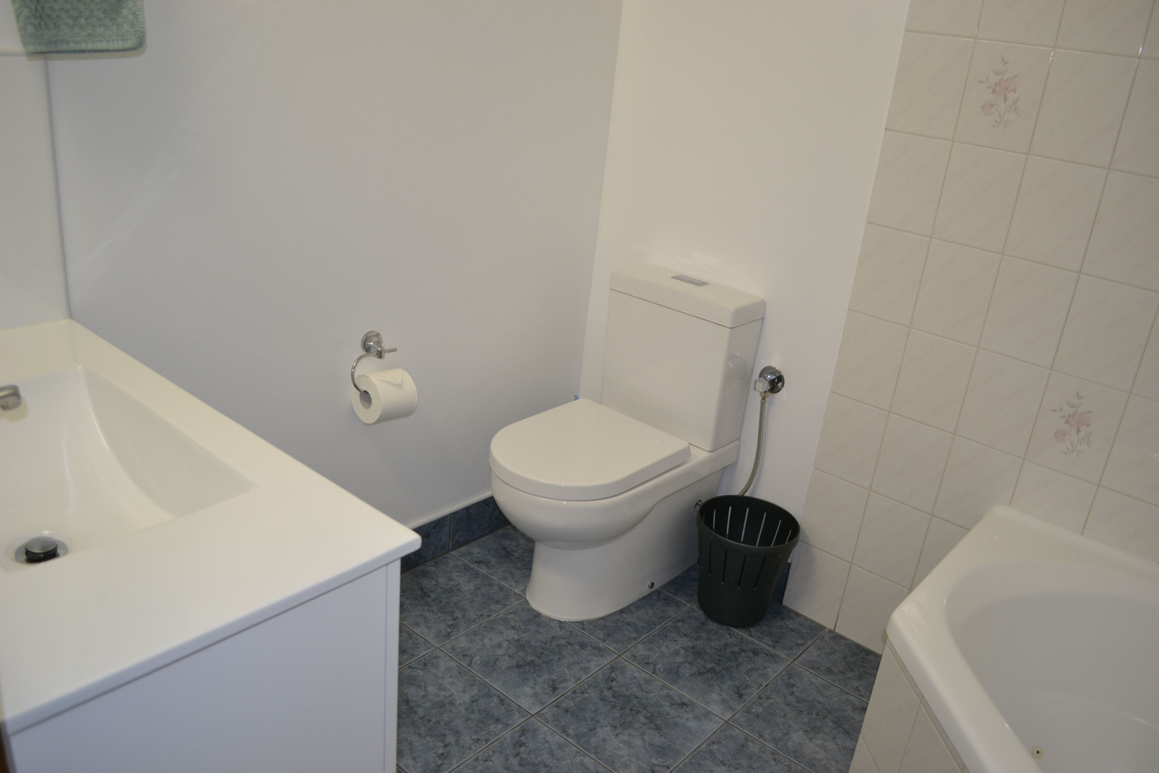 Un baño con inodoro blanco, lavamanos y bañera.