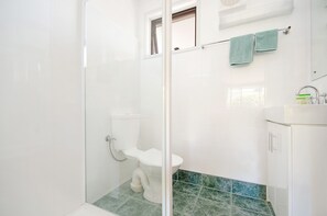 A bathroom with a glass-enclosed shower, a white toilet, and a sink with a mirror.
