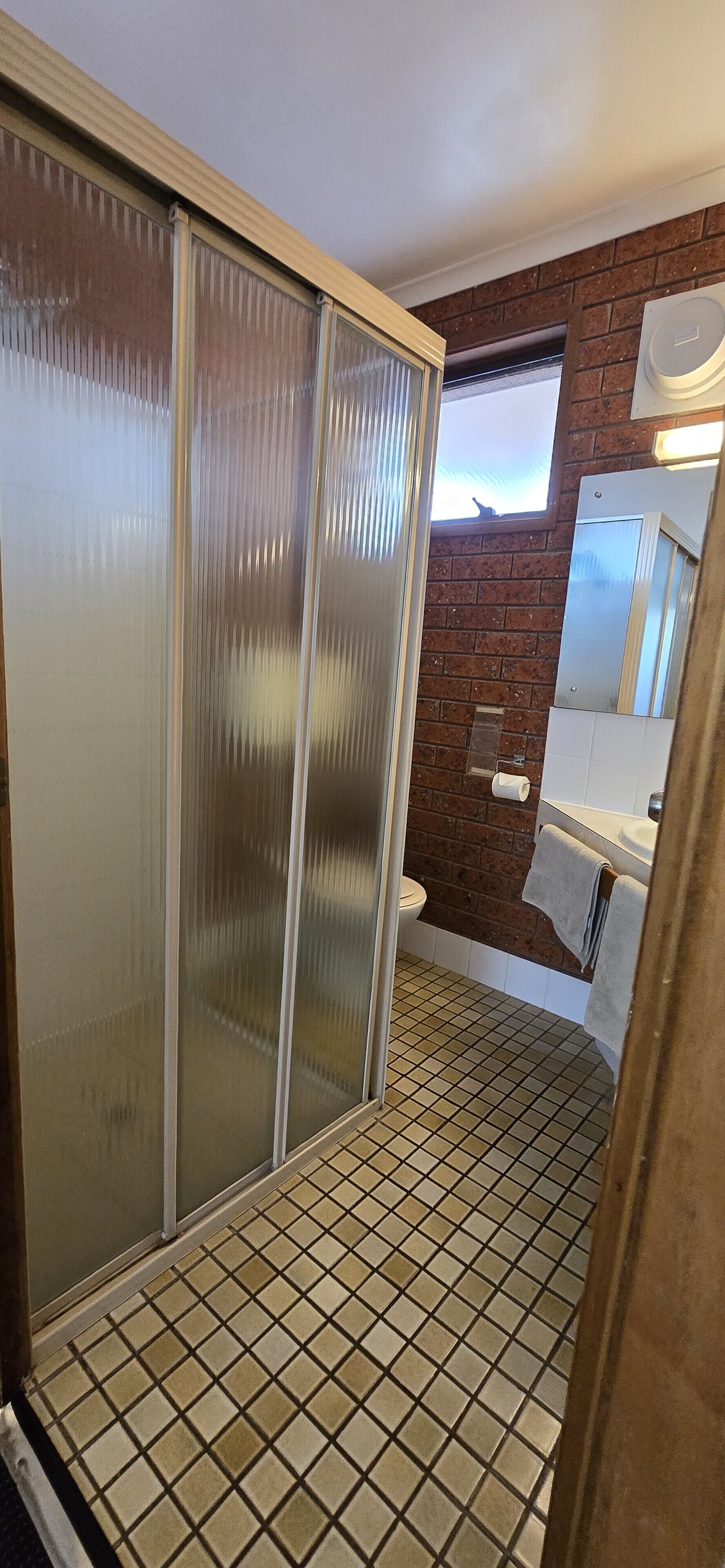 Un baño con piso de cerámica, inodoro, lavamanos y ventana.