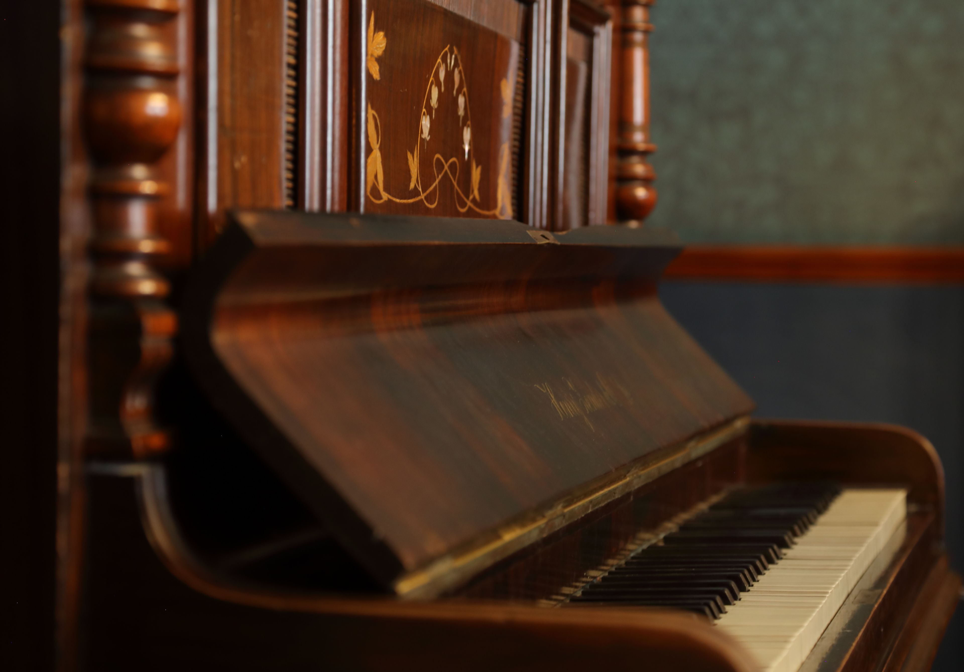 A close-up of a grand piano with a dark finish and intricate carvings on the side.