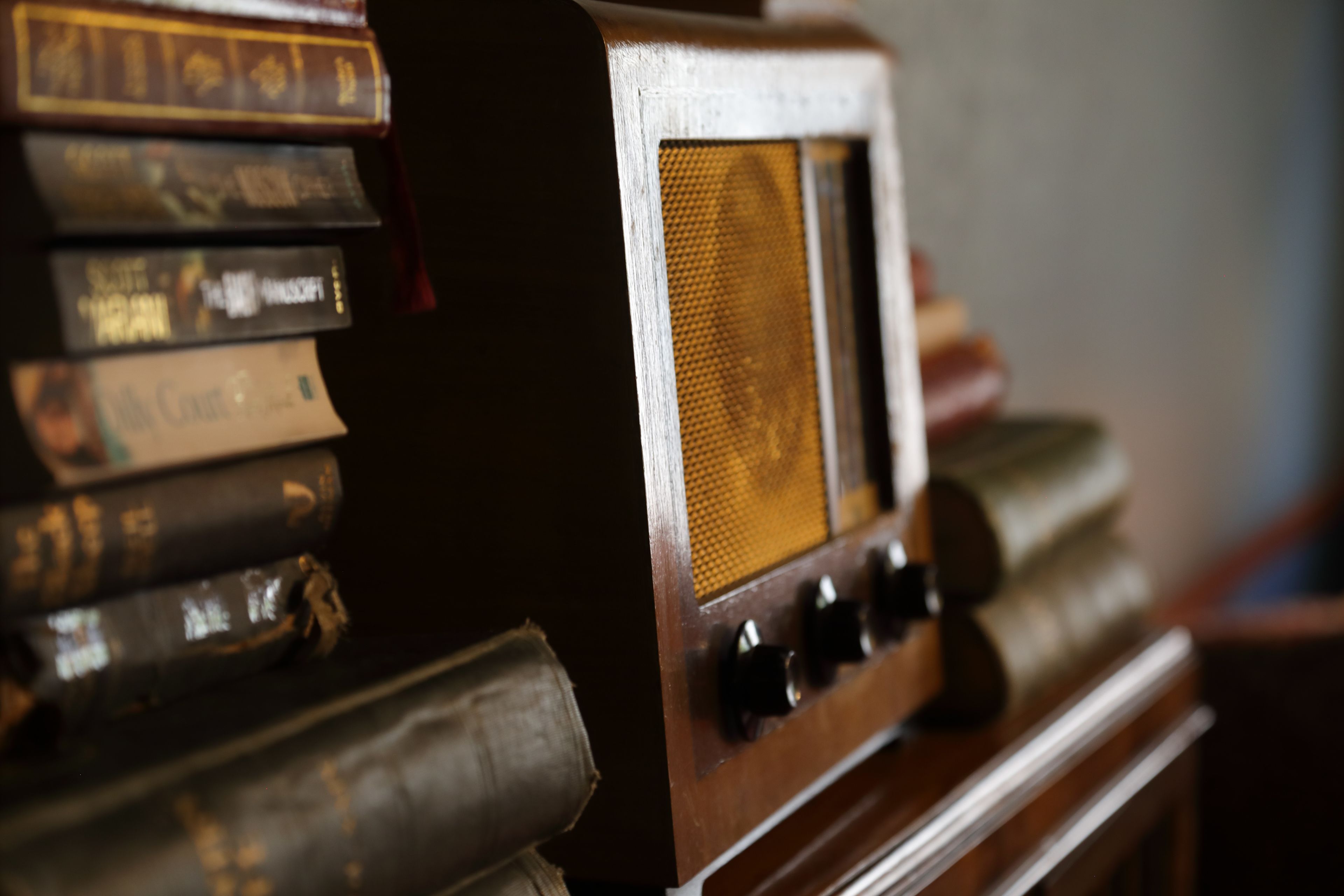 A vintage radio with a wooden cabinet and a stack of books.