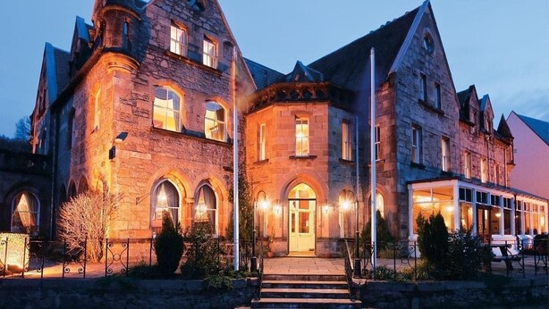 A large stone building with multiple arched windows and a prominent entrance. - Ballachulish Hotel (Ballachulish)