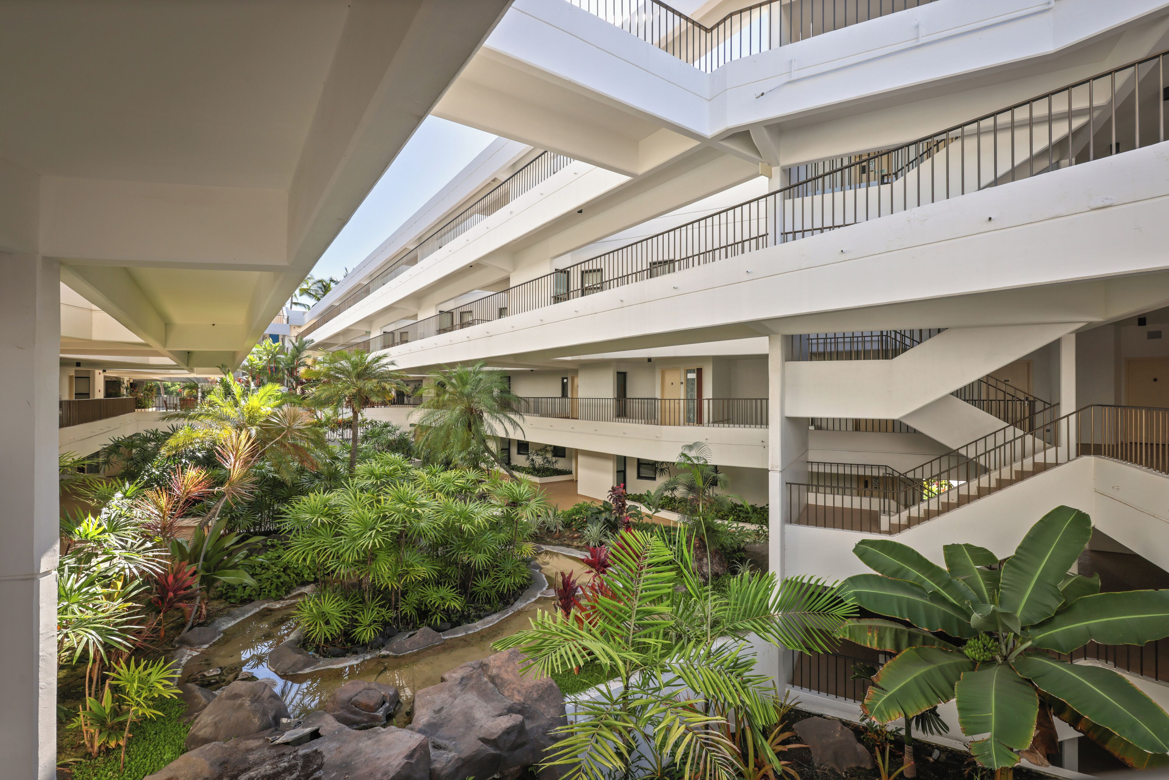 A multi-level atrium with a central garden, balconies, and staircases.
