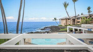 A resort with a pool, palm trees, and a view of the ocean.
