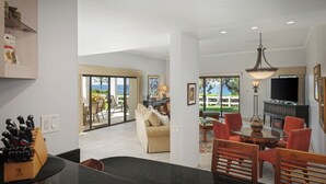 A modern kitchen with a dining area, a sofa, and a TV.