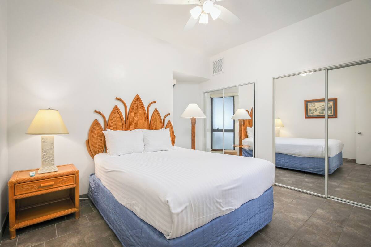 Une chambre à coucher avec un grand lit, une table de chevet avec une lampe, un miroir et une armoire.