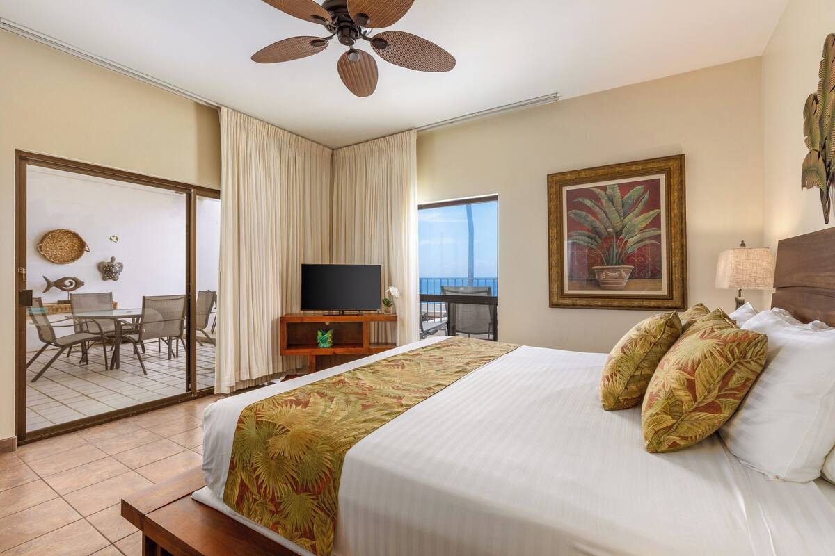 Une chambre d’hôtel comprenant un lit, une télévision, un balcon avec vue et un coin repas.
