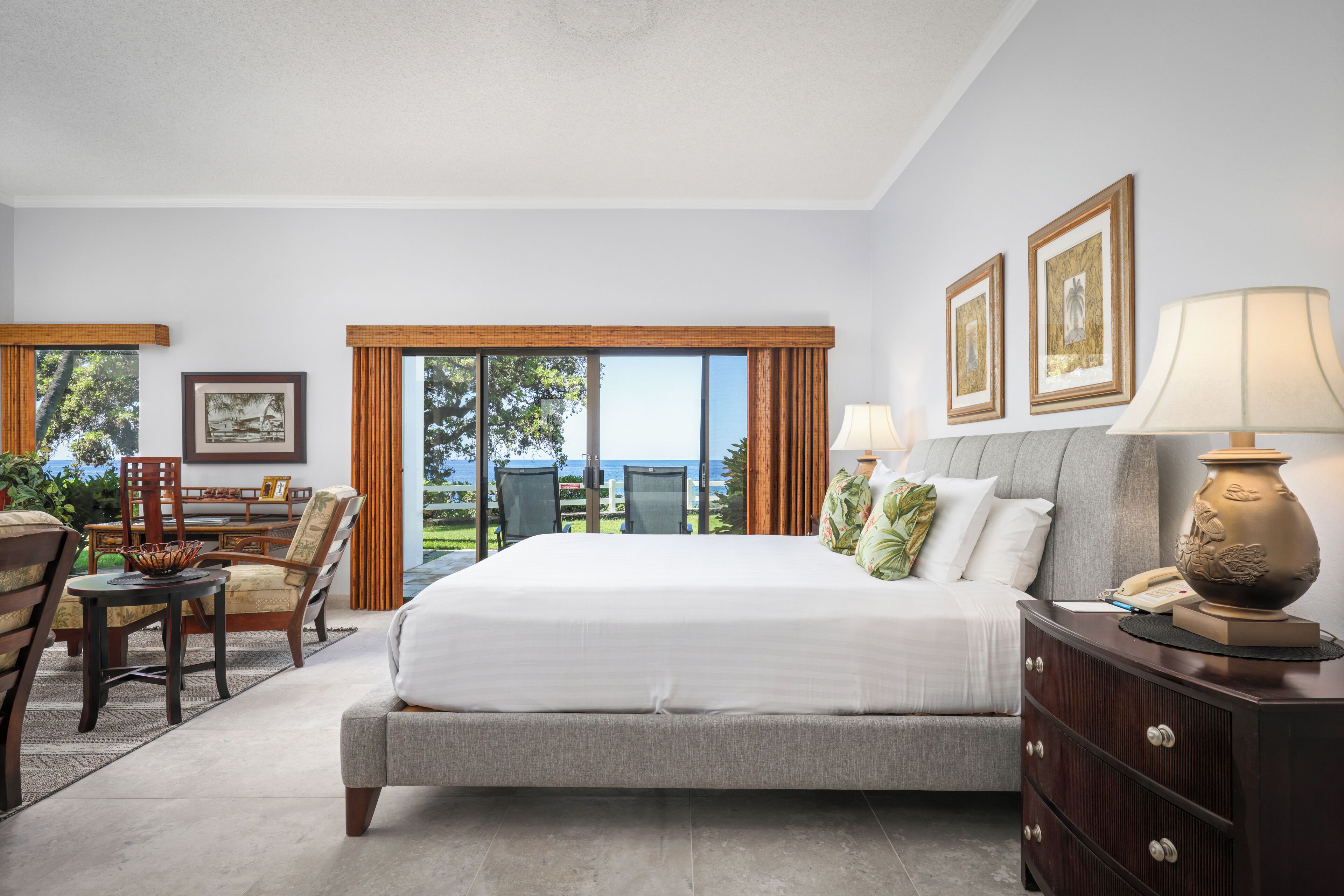 Un dormitorio moderno con una cama grande, un escritorio, sillas y vistas al exterior.