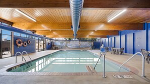 Een binnenzwembad met houten plafond, blauwe wanden en een muurschildering.