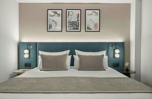 Una habitación de hotel con una cama grande, dos lámparas de noche y tres obras de arte enmarcadas en la pared.