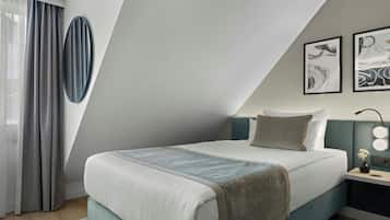 Une chambre d’hôtel moderne, équipée d’un lit, d’une table de chevet, d’une lampe et d’œuvres d’art accrochées au mur.