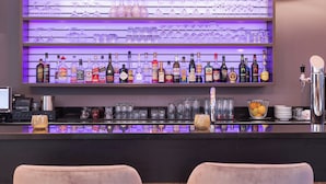 Una zona de bar con estantes llenos de botellas de licor y vasos, una barra y una caja registradora.