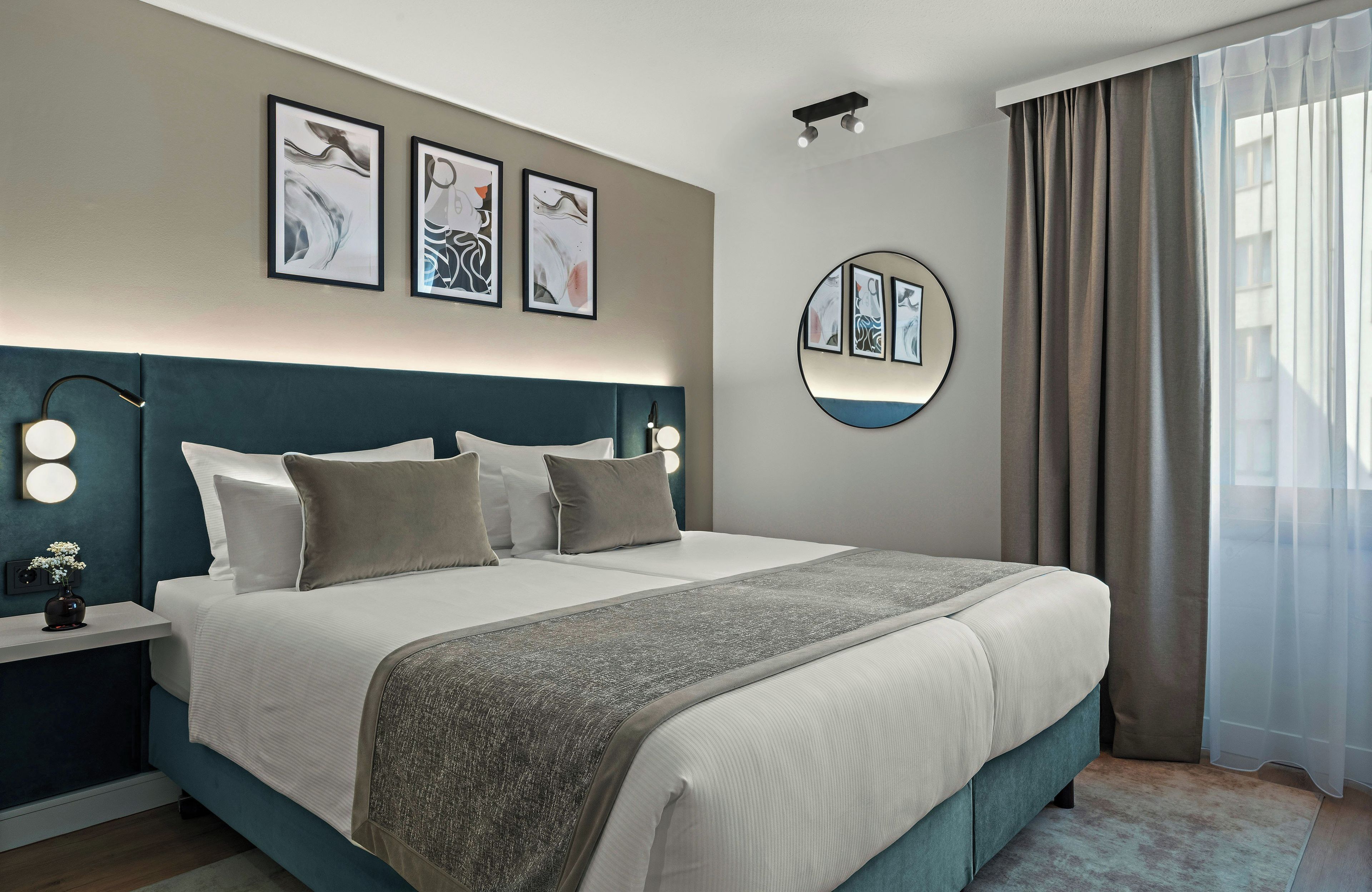 Una habitación de hotel moderna con una cama grande, lámparas de noche y obras de arte en las paredes.
