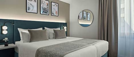 A modern hotel room with a large bed, bedside lamps, and artwork on the walls.