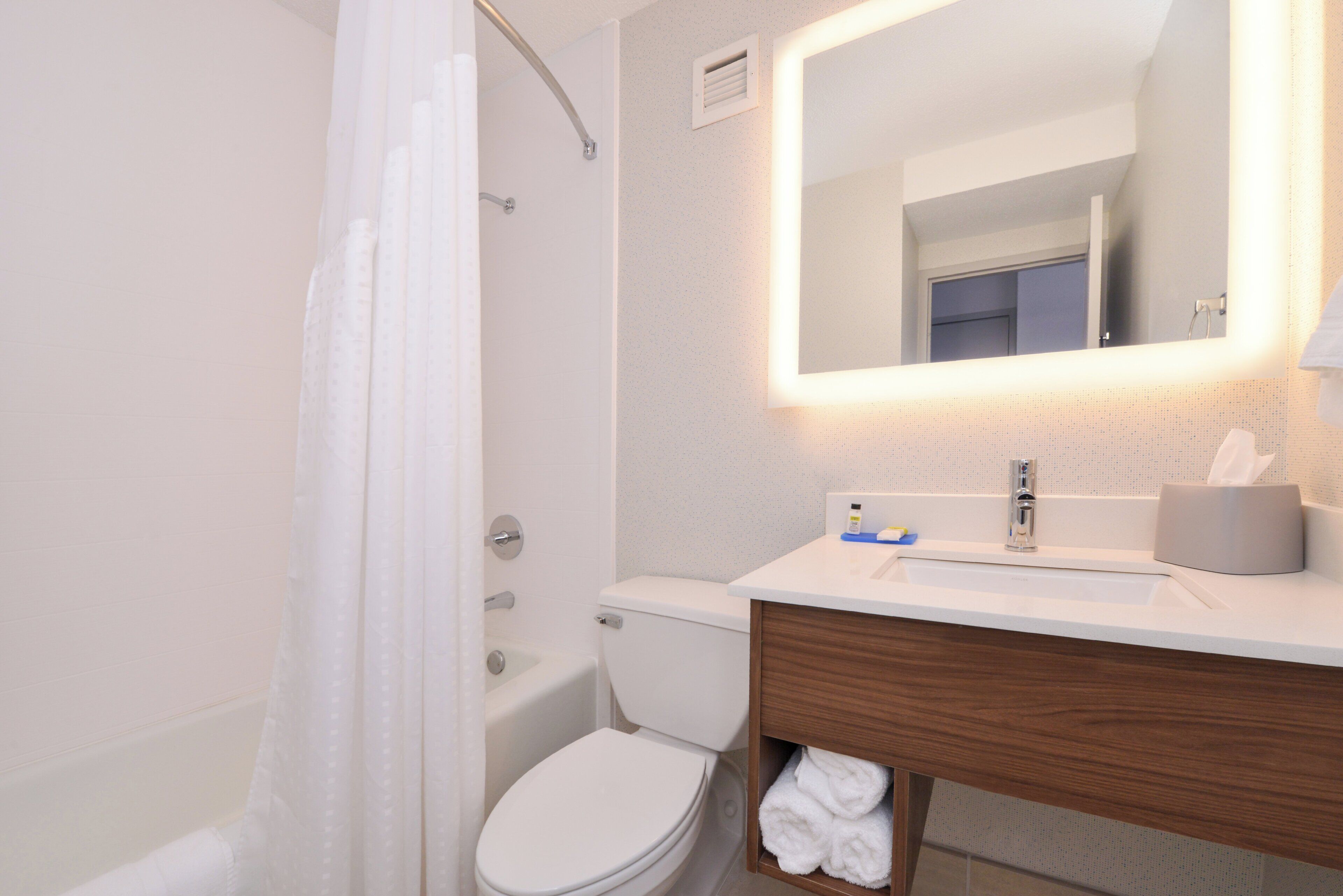 A modern bathroom with a shower, toilet, and sink.