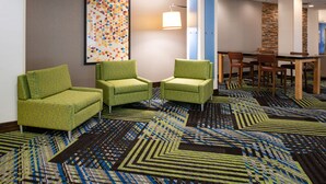 A hotel lobby with green armchairs, a wooden table, and a patterned carpet. - Holiday Inn Express Towson - Baltimore North by IHG (Towson)