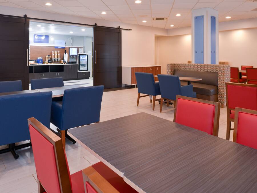 A modern dining area with blue and red booths, a central table, and a kitchen area in the background.