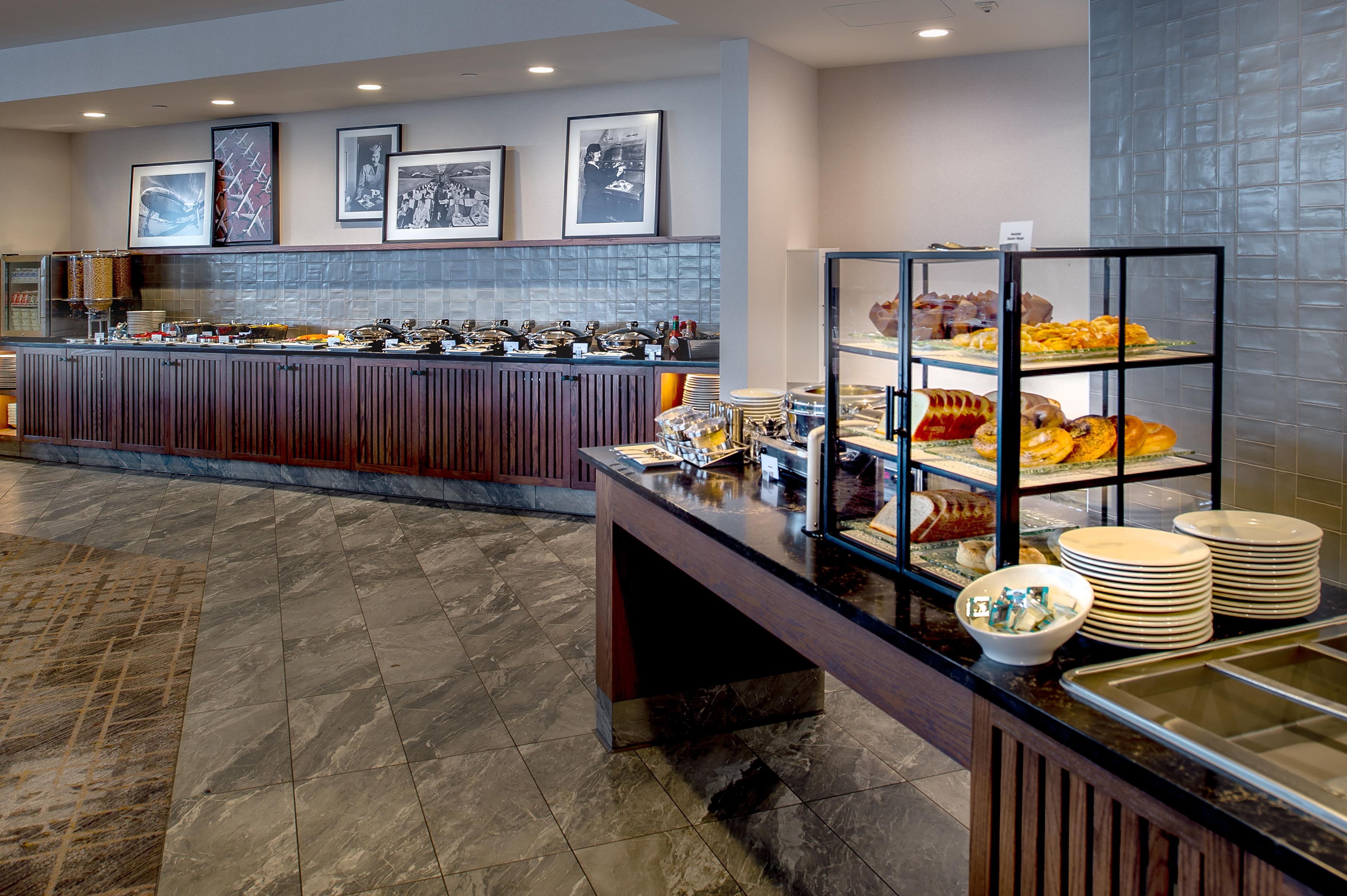 A buffet area with a marble floor, a counter with various food items, and framed pictures on the wall.