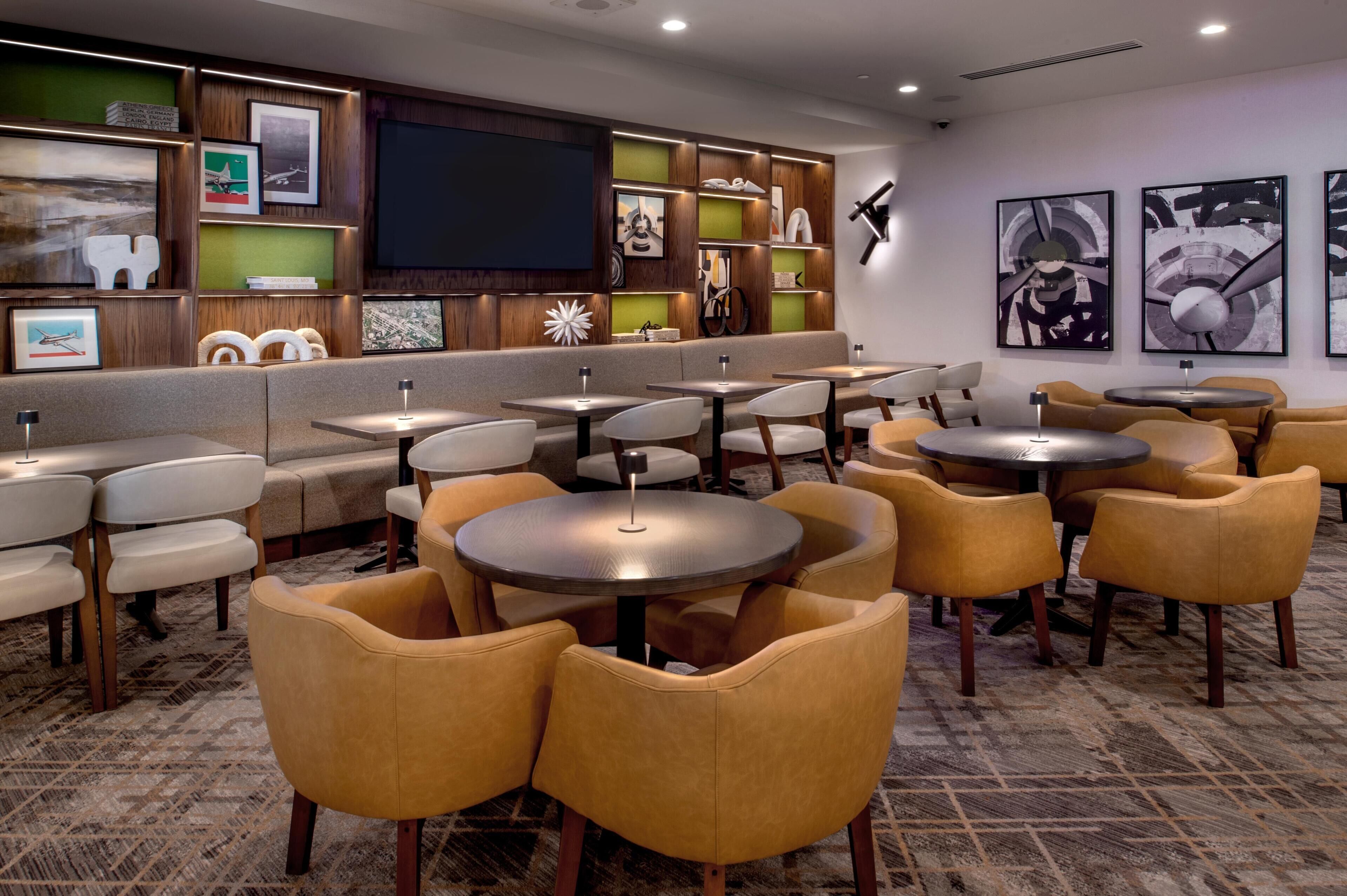 A hotel lobby with seating areas, a television, and wall-mounted artwork.