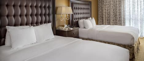 Una habitación de hotel con dos camas, una mesita de noche con lámpara y una ventana con cortinas.