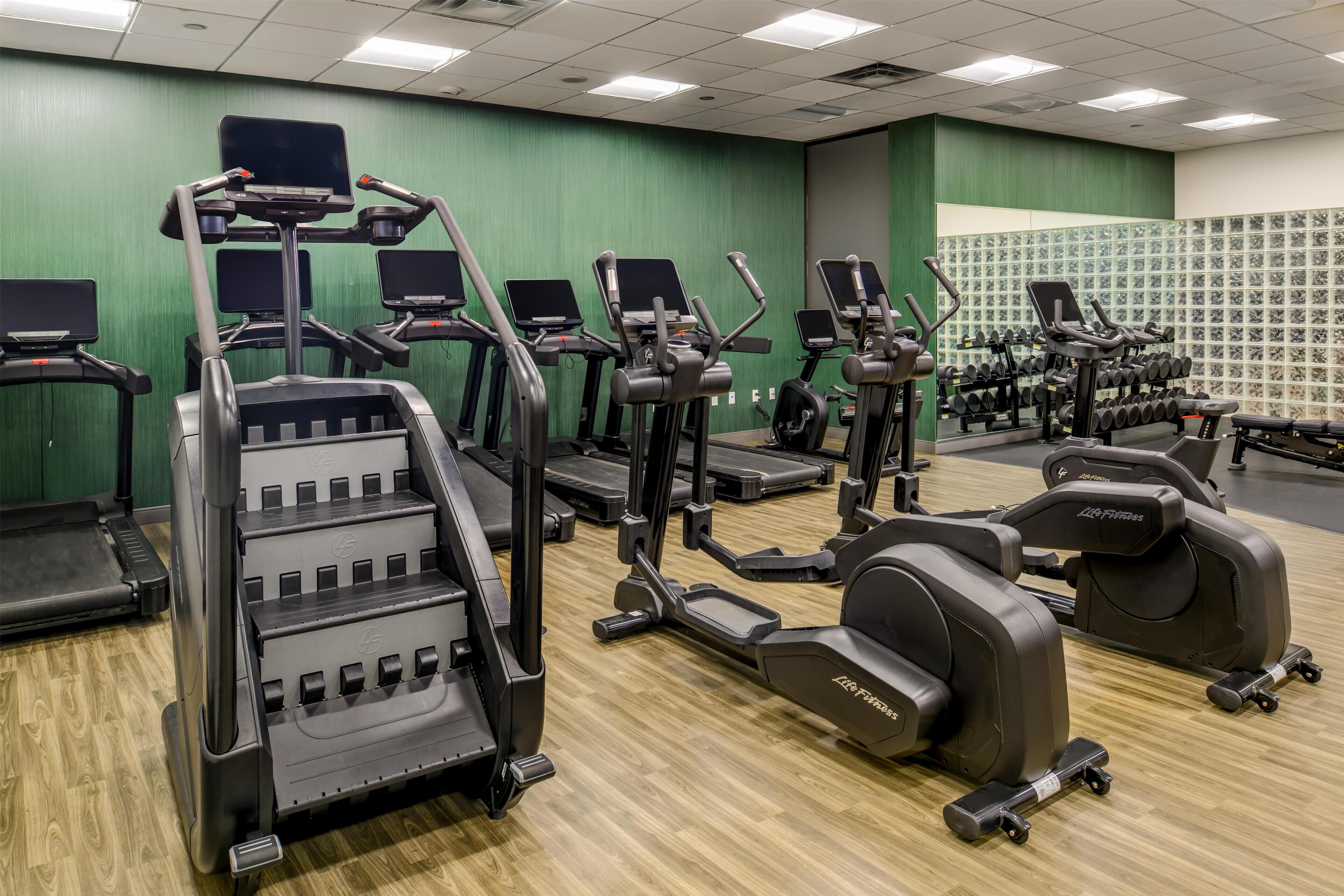 Ett gym med olika typer av träningsutrustning, inklusive löpband, crosstrainers och styrketräningsmaskiner.