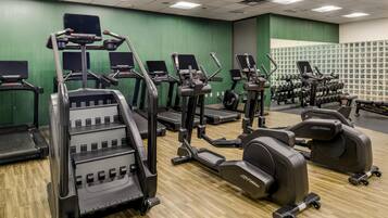Ett gym med olika typer av träningsutrustning, inklusive löpband, crosstrainers och styrketräningsmaskiner.