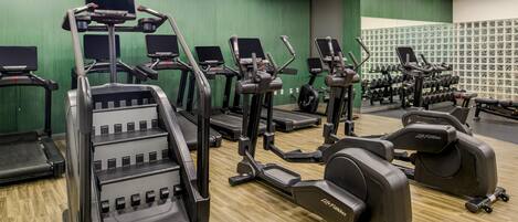 A gym with various exercise equipment, including treadmills, ellipticals, and weight machines.